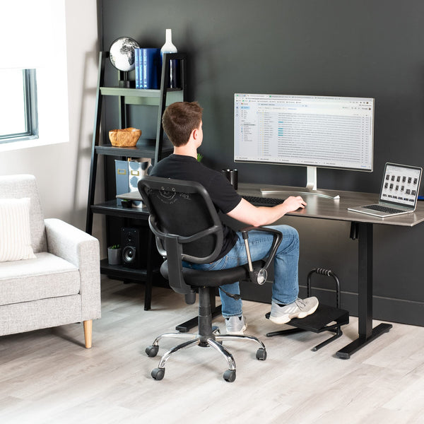 : Office worker at a desk shifting sitting position, illustrating how movement and posture relate to low back pain