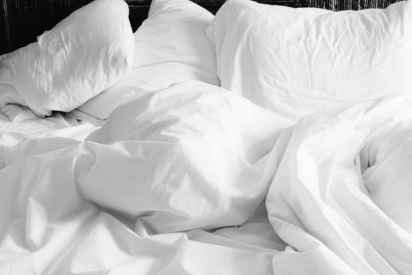 Non contoured pillow on a bed, not positioned to keep the neck aligned and ease neck pain during sleep