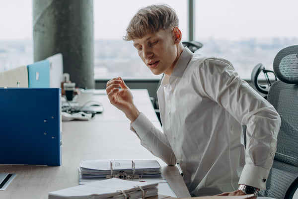 Office worker sitting for a long stretch at a desk, illustrating research on sitting duration and low back pain in 2026