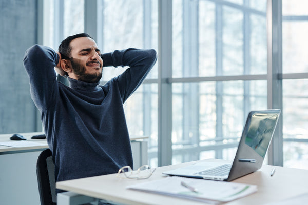 Office worker at a desk holding their low back, illustrating desk-related low back pain research in 2026